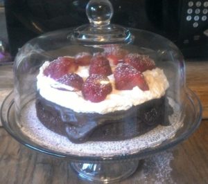 image of flourless chocolate cake with ganache, whipped cream and strawberries